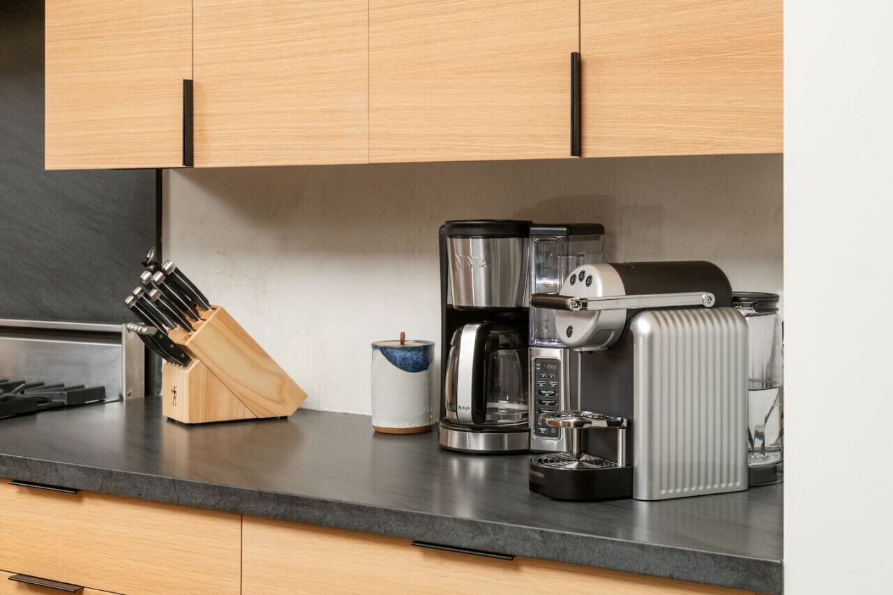 A kitchen with a coffee maker, a knife block, and a ceramic mug on the counter.