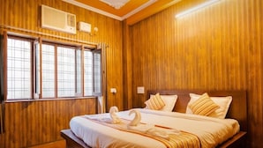 Une chambre d’hôtel avec des boiseries, un grand lit avec une literie blanche, deux oreillers et une serviette pliée en forme de cygne.