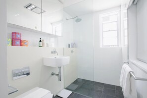 Bathroom features a white sink, glass shower, and large mirror.
