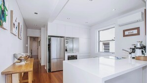 Une cuisine moderne avec des meubles blancs, des appareils en acier inoxydable et un grand îlot central.