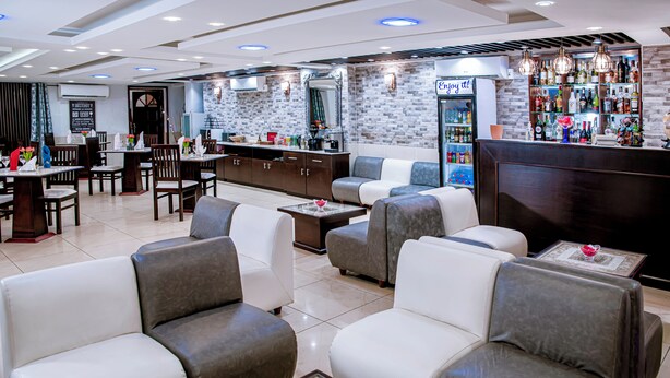 Un espacio lounge moderno con sofás, una barra y una zona de estar con mesas.