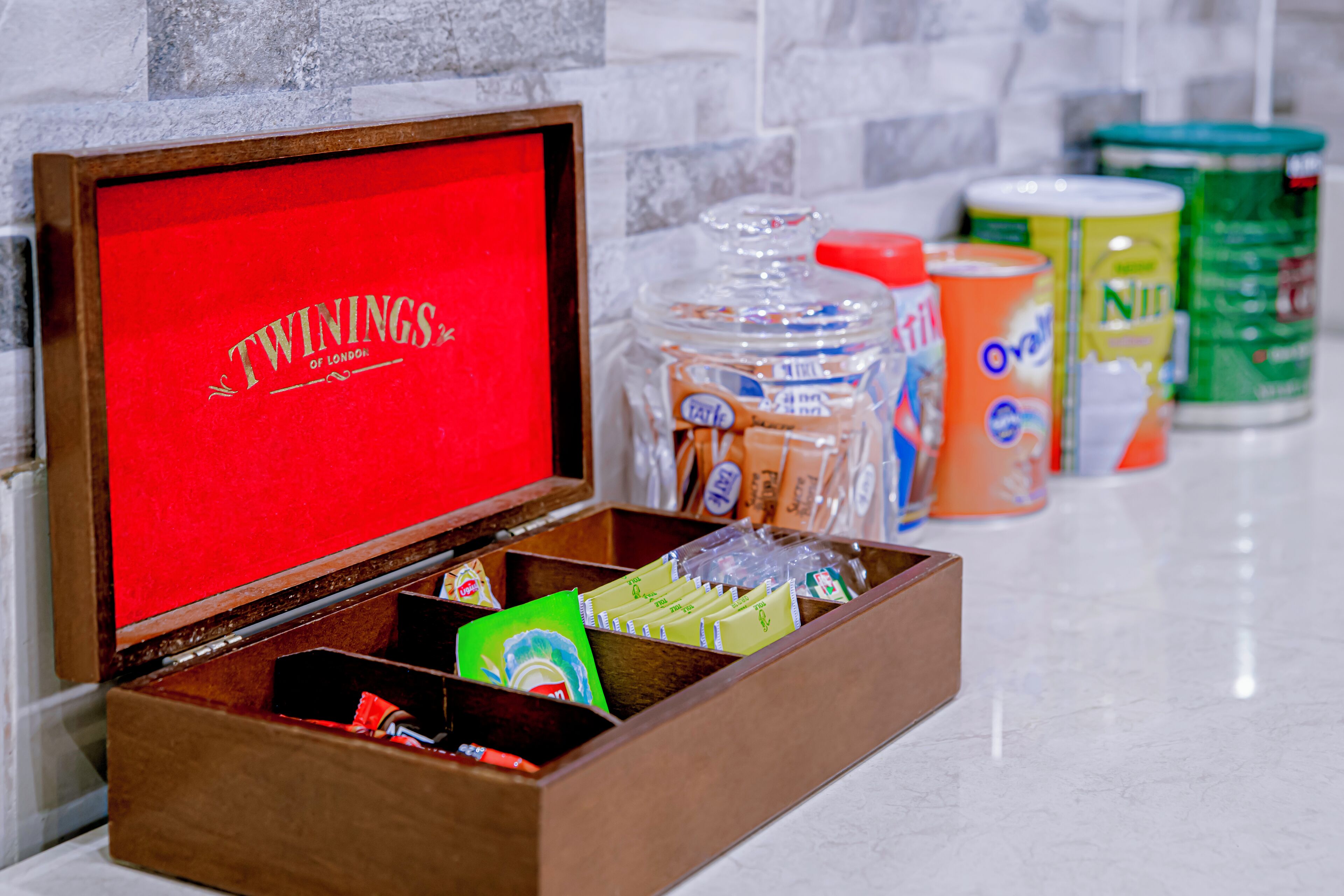 Una caja de madera con interior rojo, que contiene diversos alimentos y productos envasados.