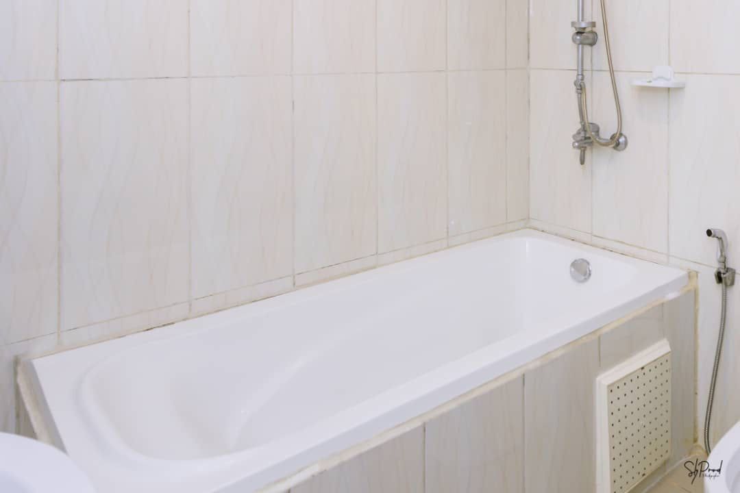 A white bathtub in a bathroom with white tiles on the walls.