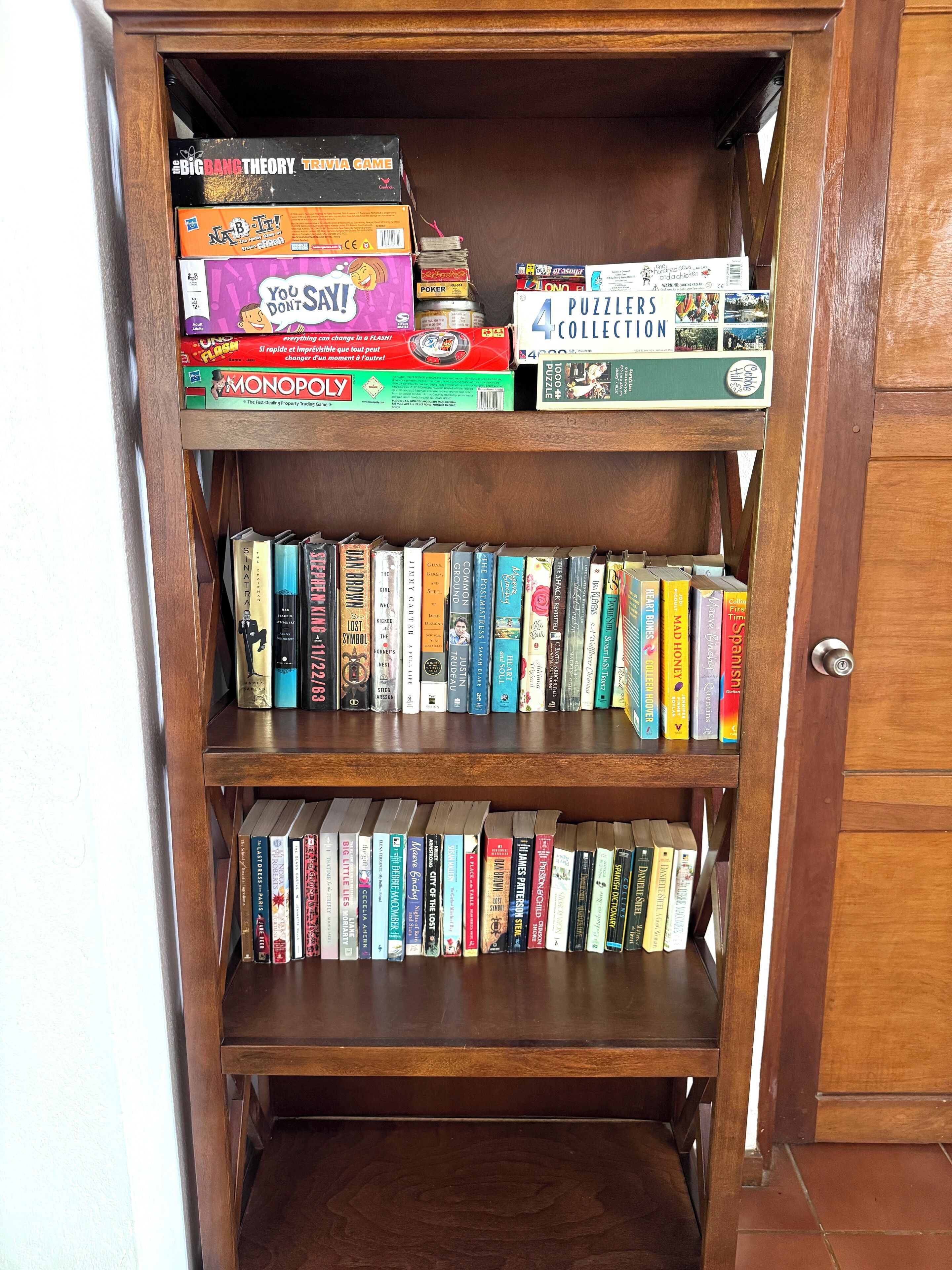 A wooden bookshelf with various board games and books.