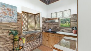 Eine kleine Küche mit Holzrückwand, einem Fenster mit Blick auf Grünflächen und einer Obstschale auf der Arbeitsplatte.