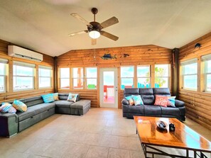 A spacious living area with a large sectional sofa, a smaller sofa, and a coffee table. - Beach Front Cottage - Head on the cloud, toes on the sand (Port Lavaca)