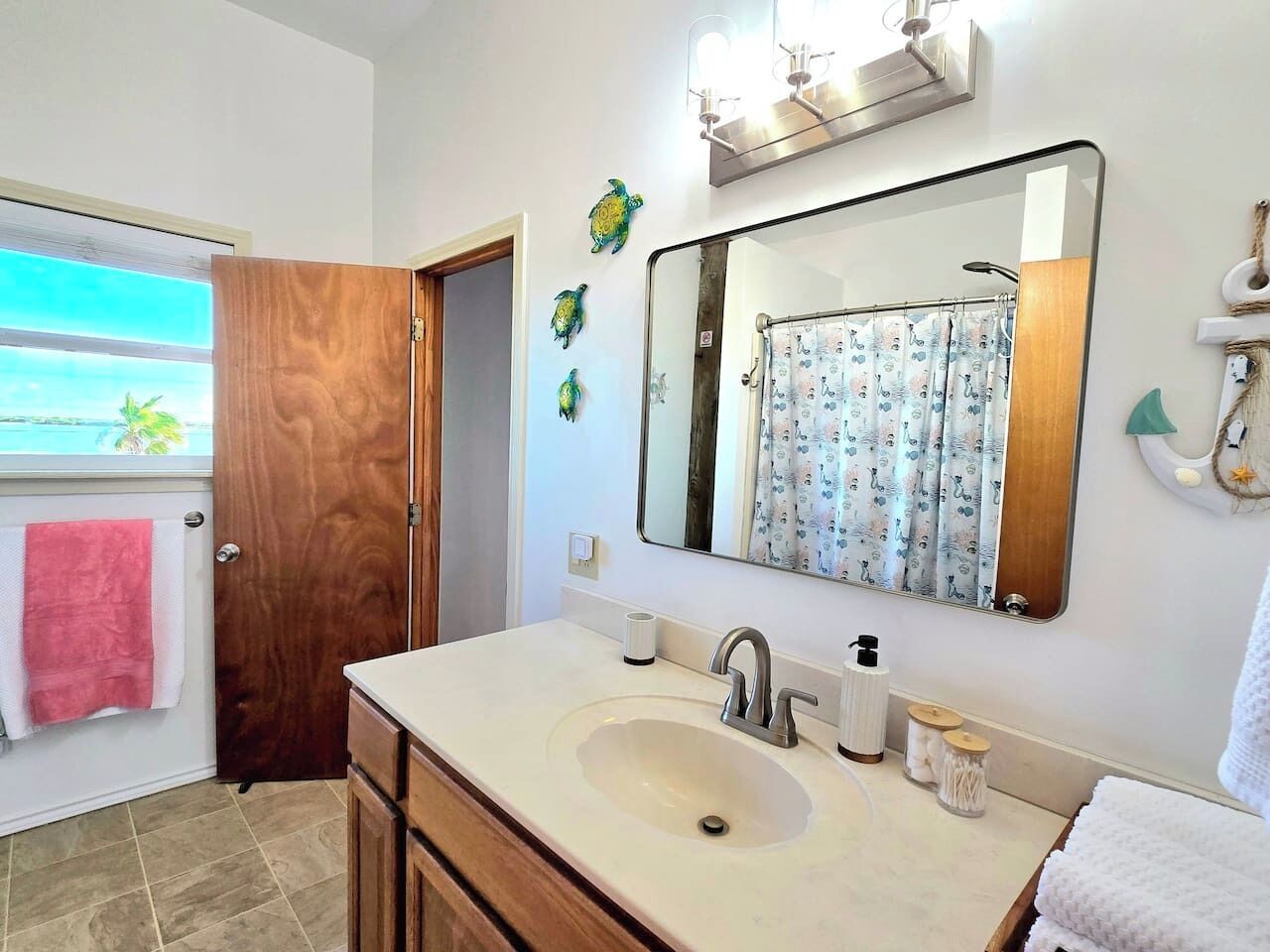 A bathroom with a large mirror, a sink, and a door leading to a balcony.