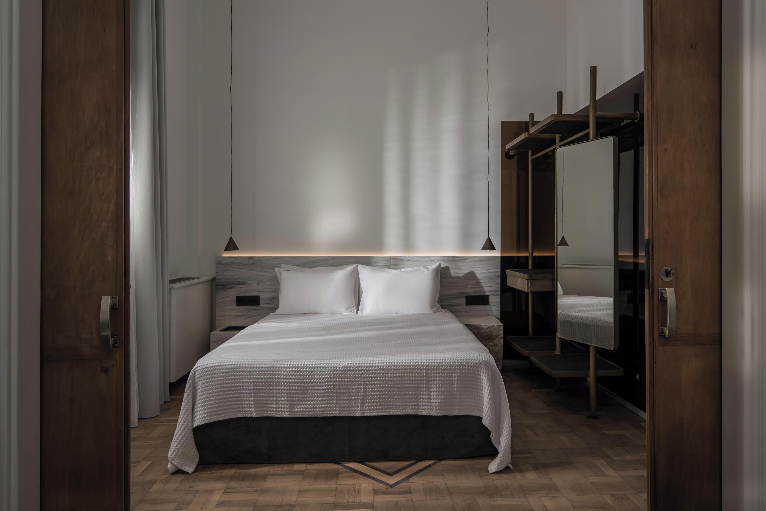 Une chambre moderne avec un grand lit, des tables de chevet, une armoire et un miroir.