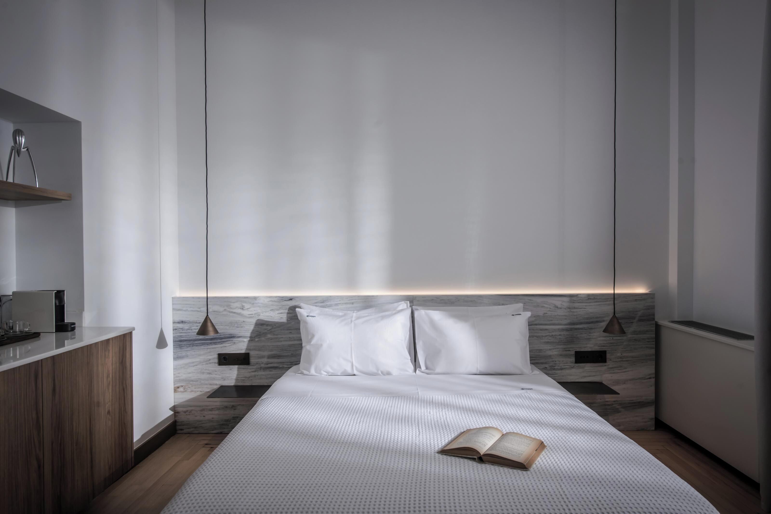 Een moderne slaapkamer met een bed, nachtkastje en bijzettafeltje.