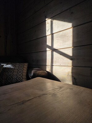A wooden cabin interior with a bed, pillows, and a table.