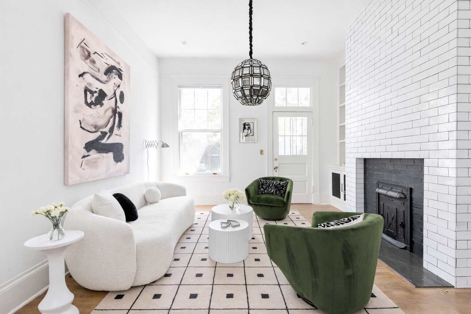 Una sala de estar con un sofá blanco, un sillón verde y una chimenea.