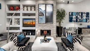 A modern living room with a fireplace, a television, and a dining area. - Zen Den Scottsdale: 2 King Suites Heated pool/Spa/Grill steps away (Scottsdale)