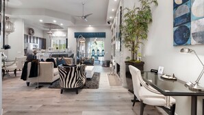 A spacious living area with a sofa, a dining table, and a large plant. - Zen Den Scottsdale: 2 King Suites Heated pool/Spa/Grill steps away (Scottsdale)