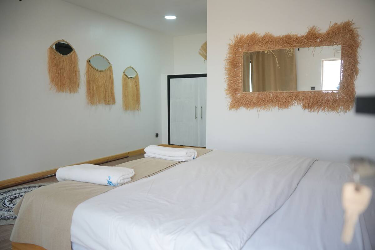 A hotel room with a bed, a mirror, and three wall-mounted mirrors.