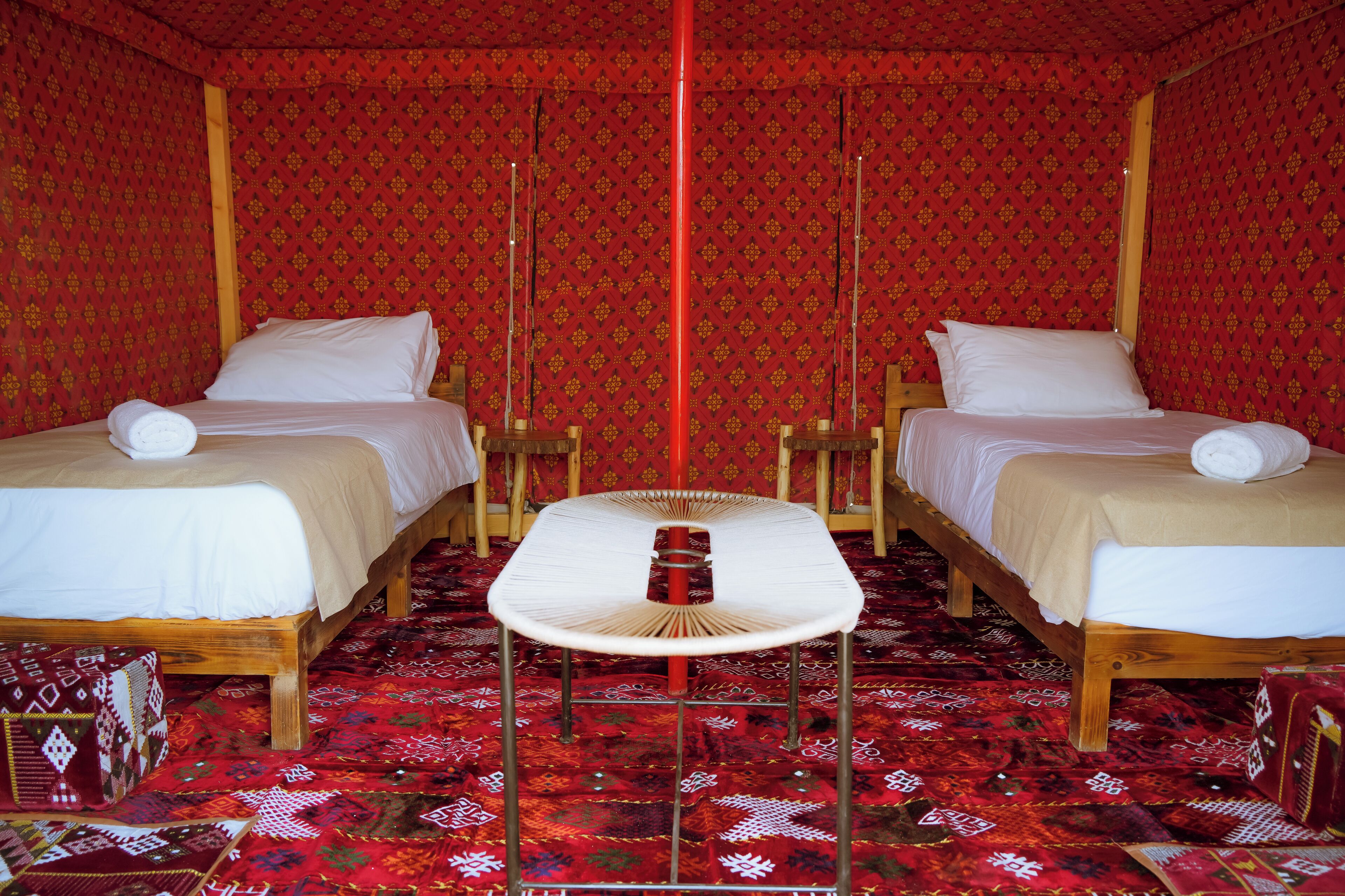 Una habitación con dos camas, una mesita y alfombra estampada.