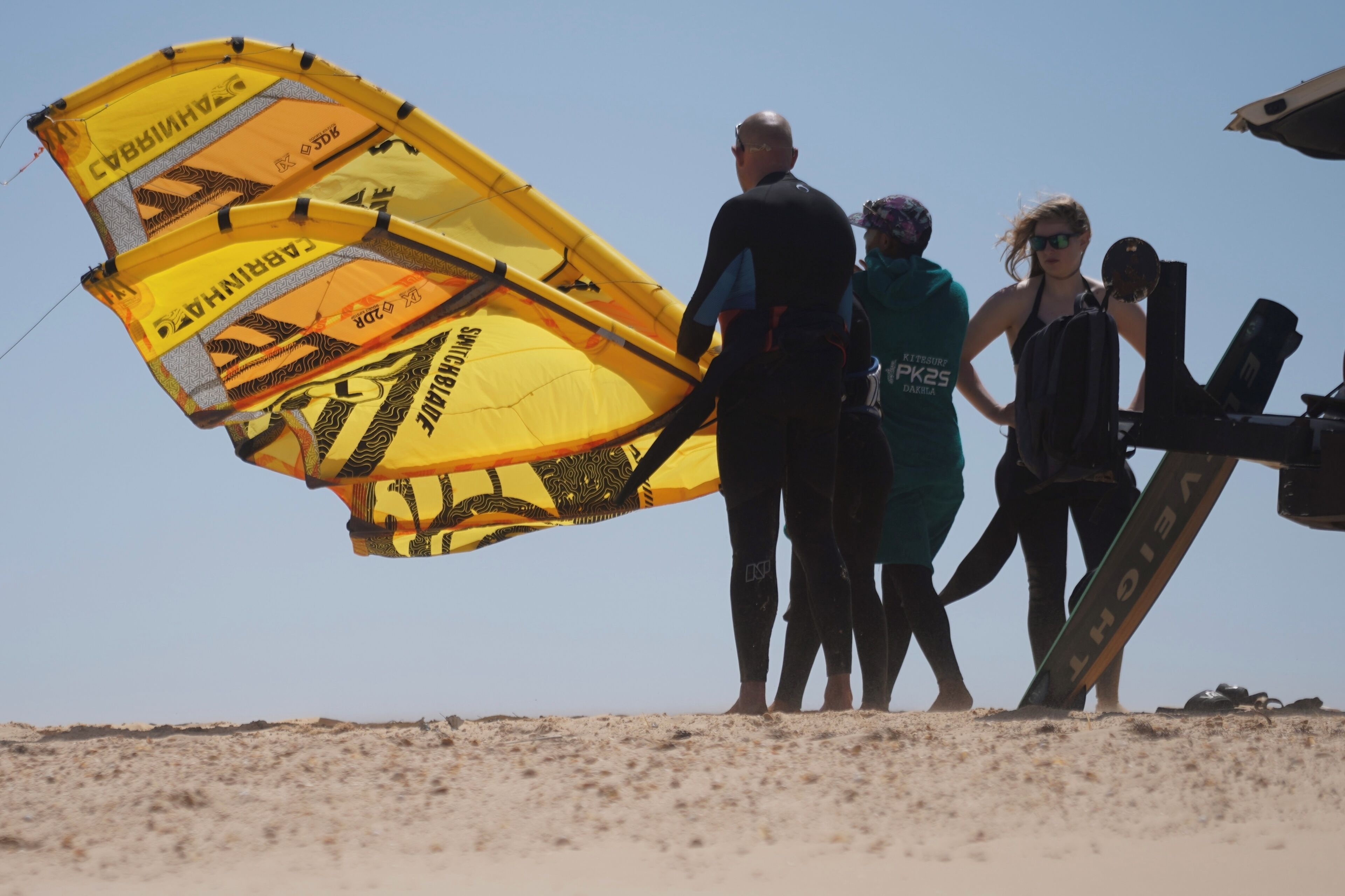 A group of people on a beach with a large yellow parachute-like structure.