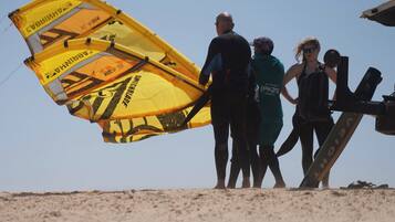 A group of people on a beach with a large yellow parachute-like structure.
