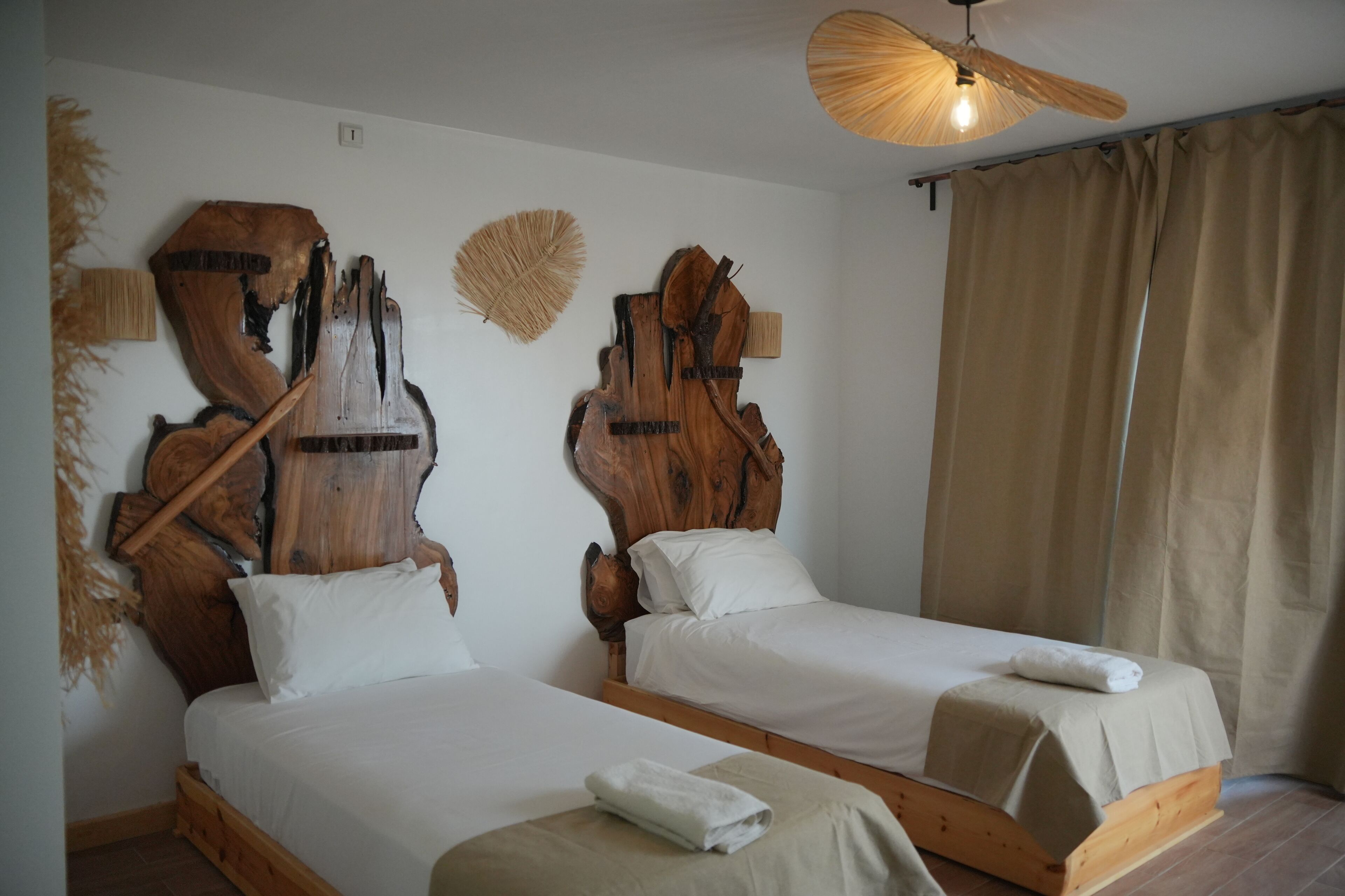 Two wooden beds with white linens and a ceiling fan.