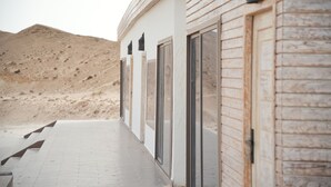 A modern building with large glass doors and windows, a wooden exterior, and a paved walkway leading to a sandy landscape. - NORTH LAGOON DAKHLA (Dakhla)