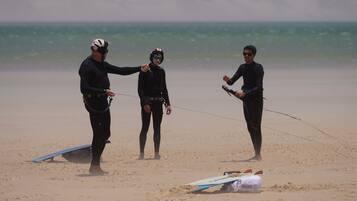 Three people on a beach with surfboards and a kite.