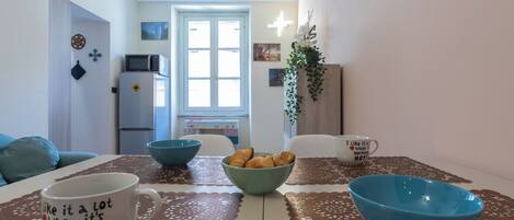 Un coin repas avec une table dressée pour deux personnes, un four à micro-ondes et un réfrigérateur en arrière-plan.