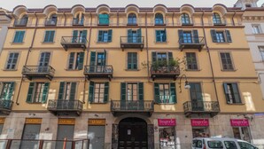 Un immeuble à plusieurs étages doté de balcons, de devantures de magasins et d’une entrée fermée pour un commerce.