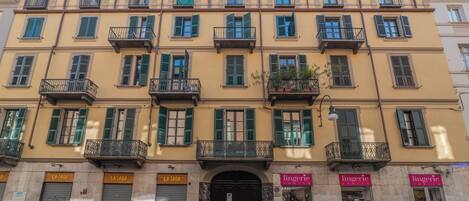 Un edificio de varios pisos con balcones, locales comerciales y la entrada de una tienda cerrada.