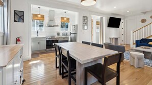 Une cuisine moderne avec des meubles blancs, une table à manger en bois et une grande fenêtre.