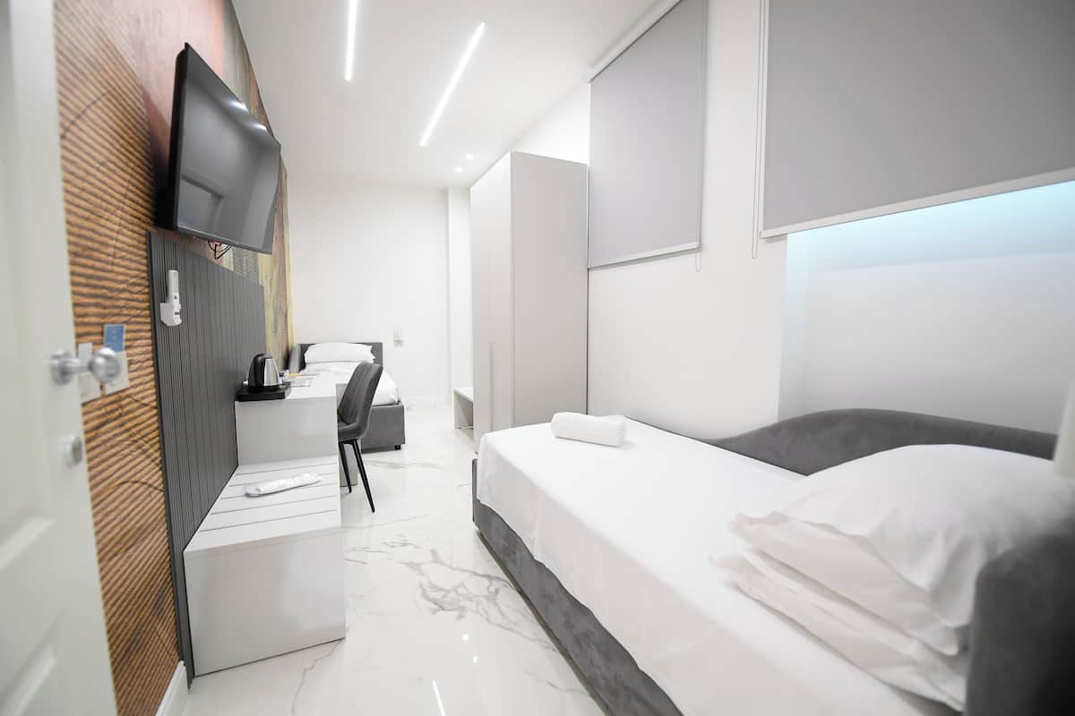 Une chambre d’hôtel moderne équipée d’un lit, d’un bureau et d’un téléviseur fixé au mur.