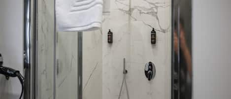 A modern bathroom with a glass shower enclosure, a handheld showerhead, and two wall-mounted showerheads.