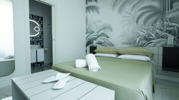 A hotel room with a bed, a bedside table with towels, a mirror, and a wall with a tropical mural.