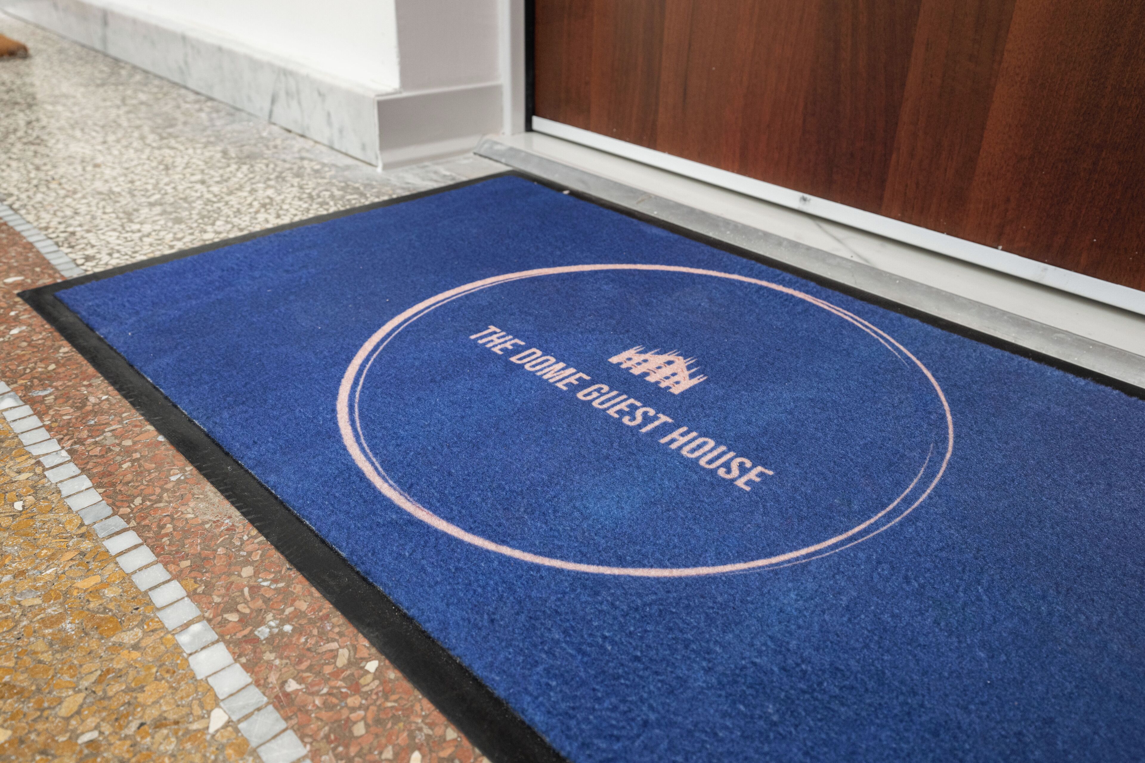 A blue doormat with the text "THE DOME GUEST HOUSE" and a logo.