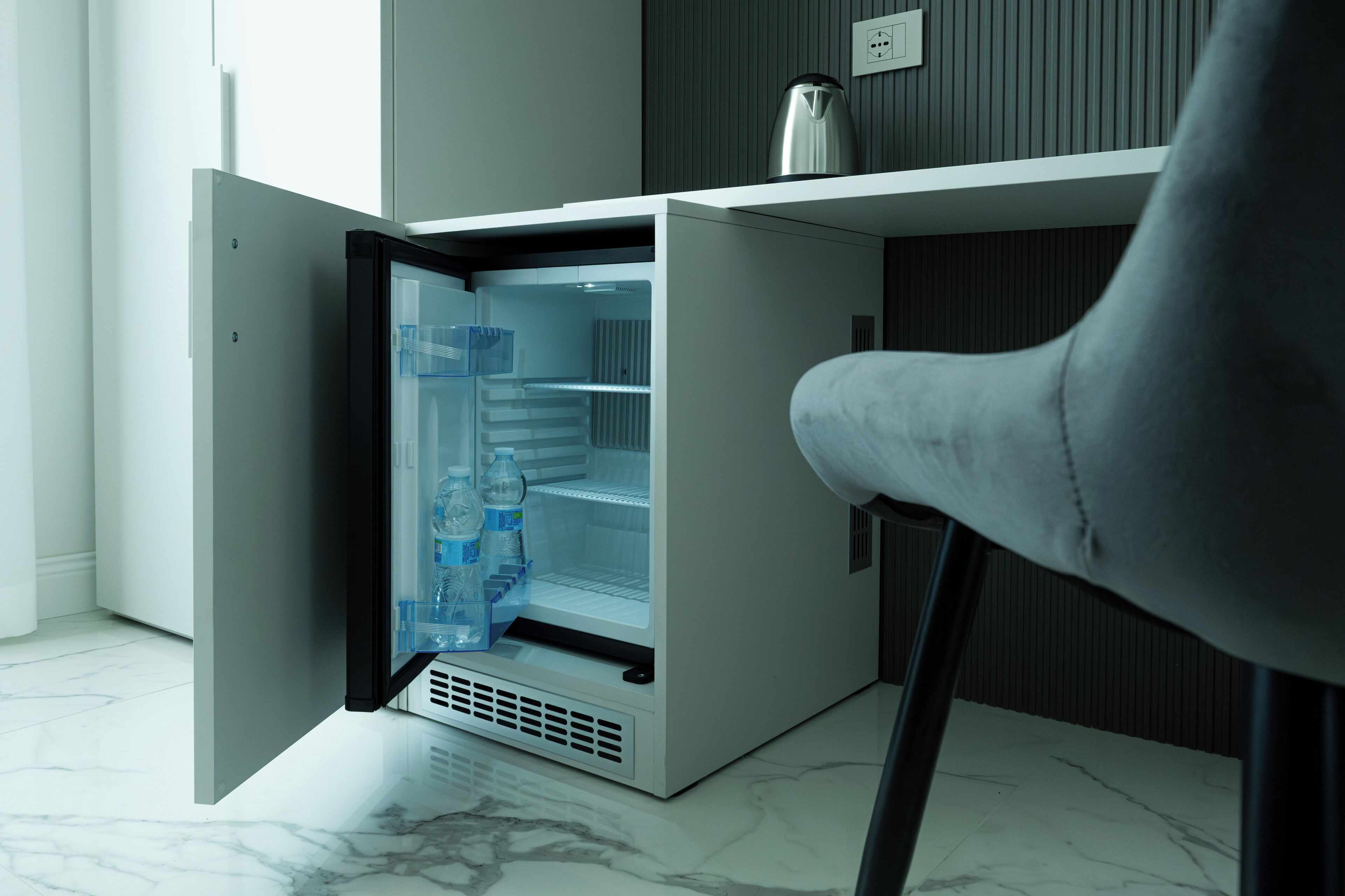 Un réfrigérateur compact doté d’un compartiment congélateur, installé dans une cuisine moderne au sol en marbre.
