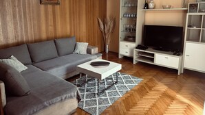 A living room with a grey sofa, a white coffee table, a TV stand, and a wooden floor. - Cozy 2-bedroom apartment in small place Ostrvica near Omiš (Ostrvica)