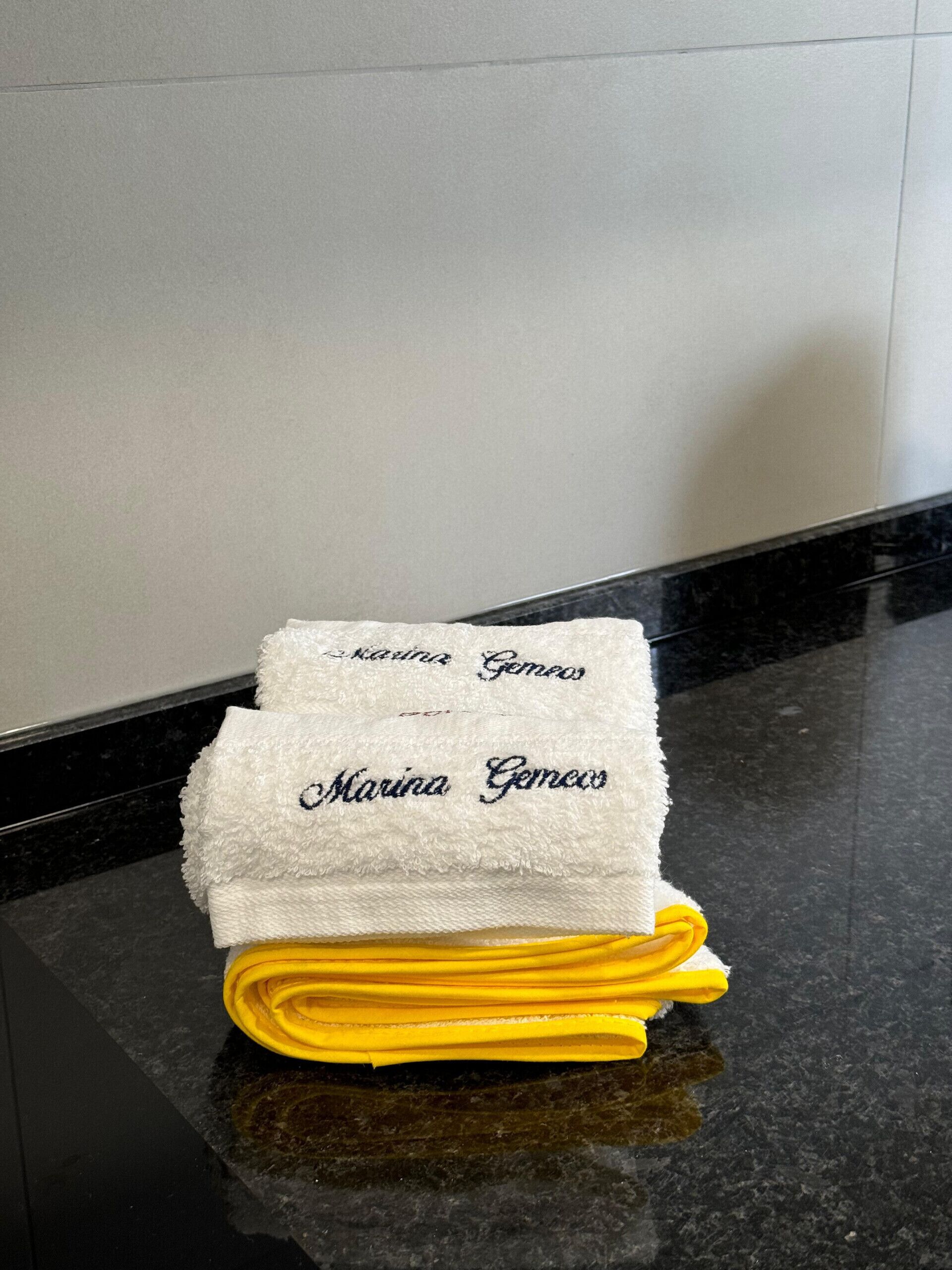 A folded white towel with embroidered text on a black countertop.