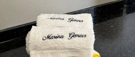 A folded white towel with embroidered text on a black countertop.