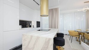 Una cocina moderna con una isla de mármol, taburetes negros y una zona de comedor con sillas amarillas.
