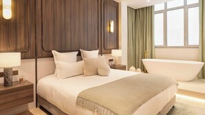 A modern bedroom with a large bed, a bathtub, and a view of the outdoors. - Exceptional 3BR/3BA w/ Services - Champs-Elysées (Paris)