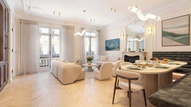 A spacious living room with a large sofa set, a dining area with a round table, and a fireplace. - Exceptional 3BR/3BA w/ Services - Champs-Elysées (Paris)