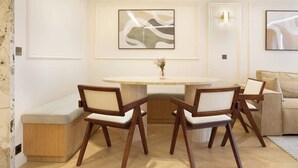 A modern living room with a round dining table, two wooden chairs, a sofa, and abstract wall art. - A Splendid 2-BR/2BA with Services in Opéra (Paris)
