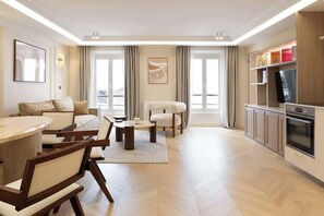 A modern living room with a dining area, a kitchen, and a large window providing natural light. - A Splendid 2-BR/2BA with Services in Opéra (Paris)