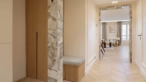 A hallway with a marble column, wooden wardrobe, bench, and a view into a room with a bed and a window. - A Splendid 2-BR/2BA with Services in Opéra (Paris)