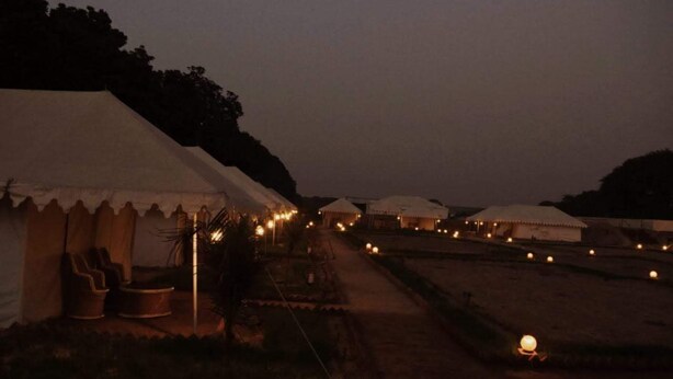 A row of tents with a pathway leading through them, suggesting a campsite or temporary accommodation. - KUMBH CAMP OM (Karchana)