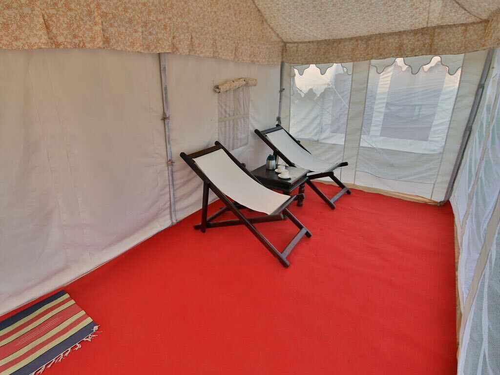 A tent with two reclining chairs and a small table with a bottle and cup.