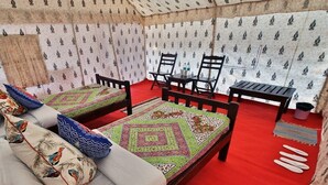 A tent-style room with two beds, each with patterned bedding and pillows, a small table, and chairs. - KUMBH CAMP OM (Karchana)