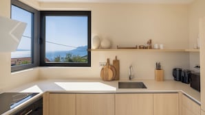 Une cuisine moderne dotée d’une grande fenêtre, de meubles en bois, d’un four encastré et d’un évier.