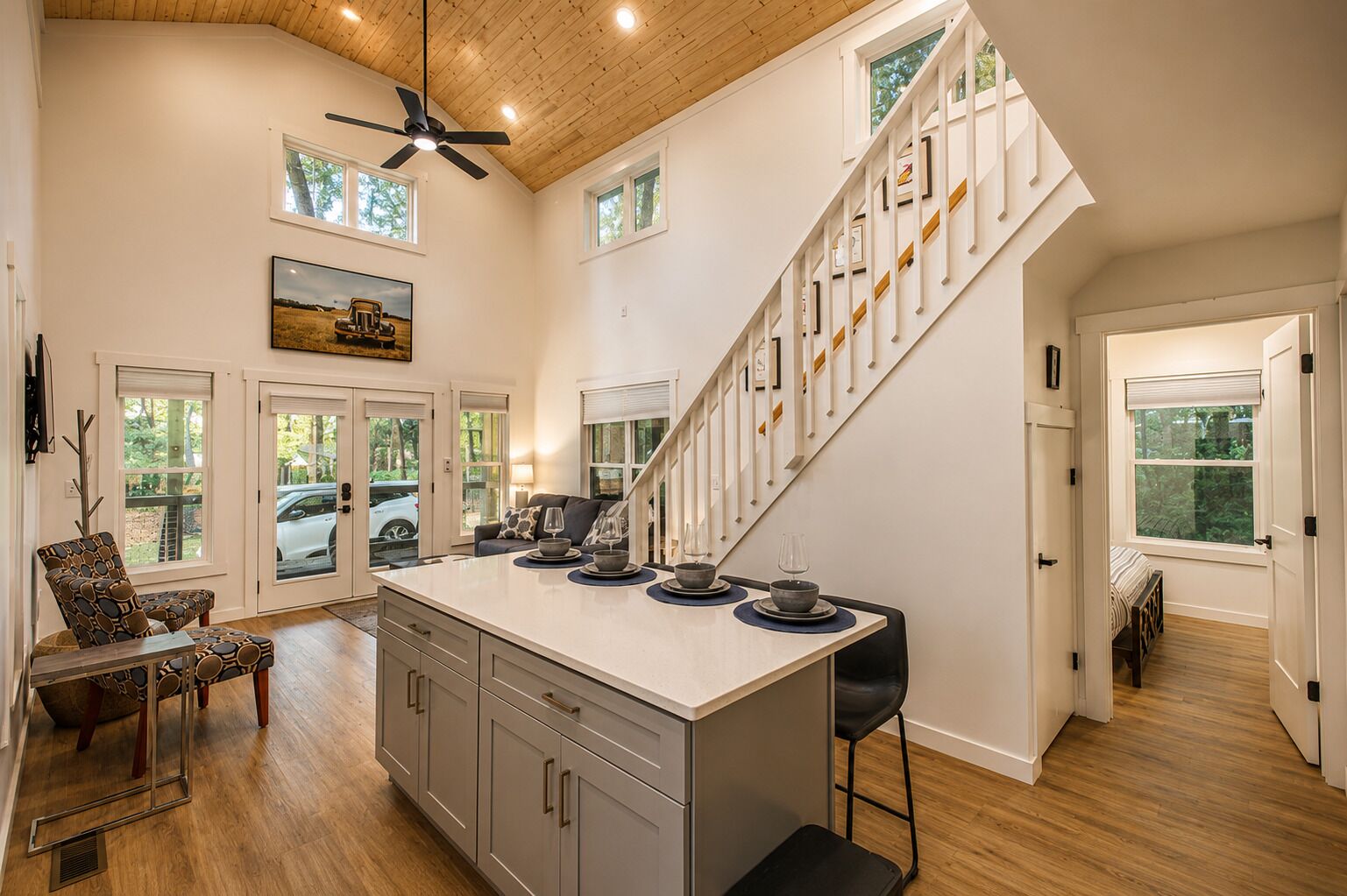 A spacious kitchen with a central island, a dining area with a table and chairs, and a staircase leading to another level.