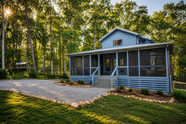 A two-story house with a porch, surrounded by a forest.