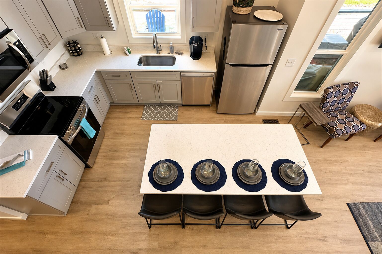 A modern kitchen with a central island, stainless steel appliances, and a dining area with four chairs.