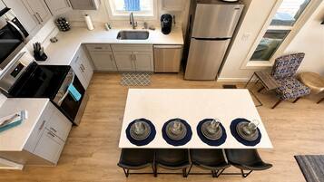 A modern kitchen with a central island, stainless steel appliances, and a dining area with four chairs.